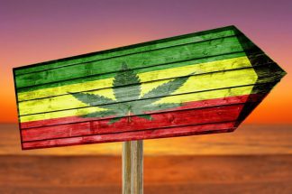Rasta Flag With Marijuana Leaf wooden sign on beach background